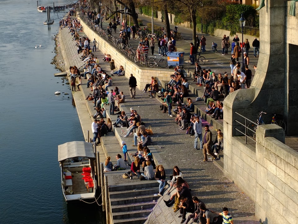 Leute sitzen am Rheinufer in der Sonne