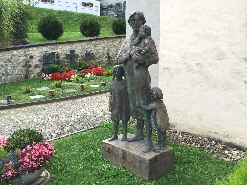 Metallskuptur von einer Frau mit drei Kindern.
