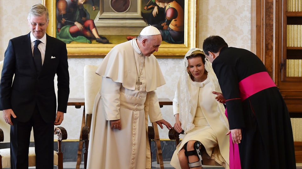 König Philippe, Papst Franziskus, Königin Mathilde und ein Papst-Mitarbeiter stehen in einem Raum.