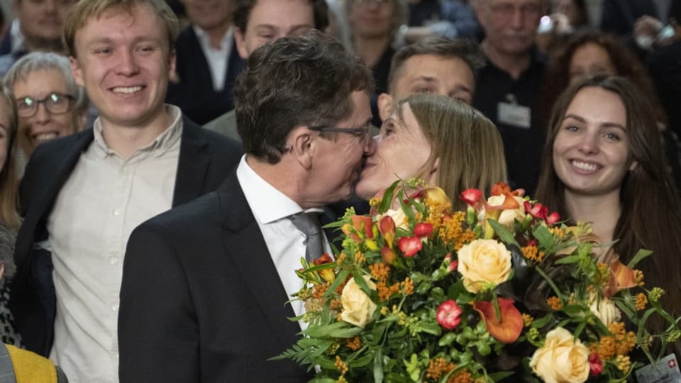 Ein Mann und eine Frau küssen sich hinter einem Blumenstrauss. 