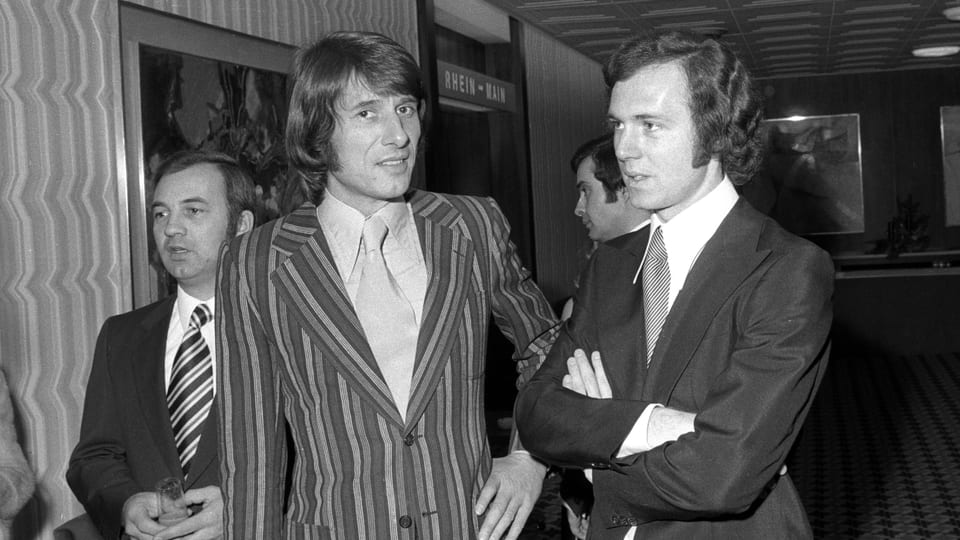 Schwarz-weiss-Foto mit Fussballer Franz Beckenbauer neben Sänger Udo Jürgens in festlicher Kleidung.