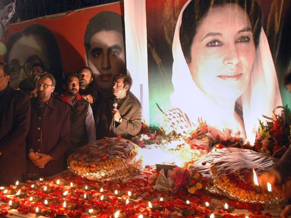 Bild von Benazir Bhutto neben trauernder Gemeinde am Jahrestag 2009.