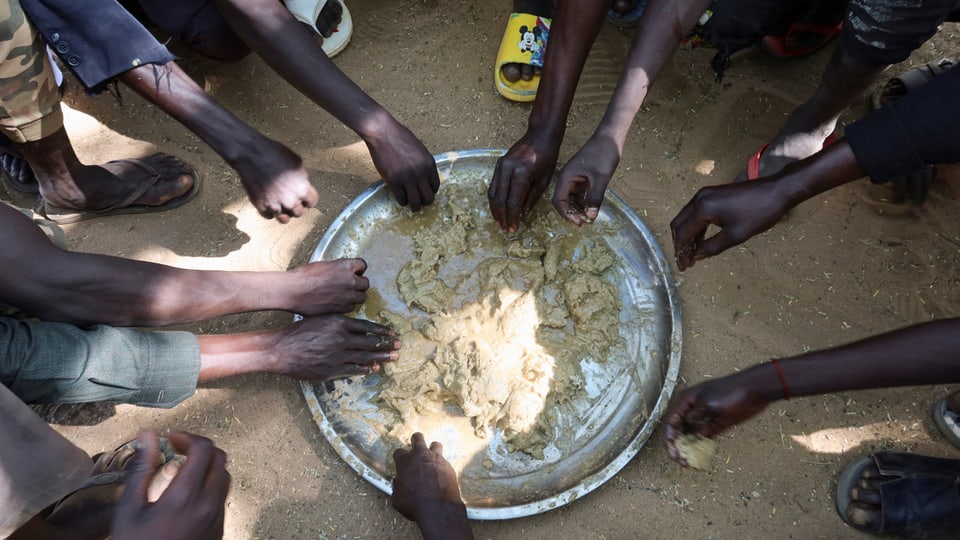 Menschen essen in einem Flüchtlingscamp im Sudan, November 2023