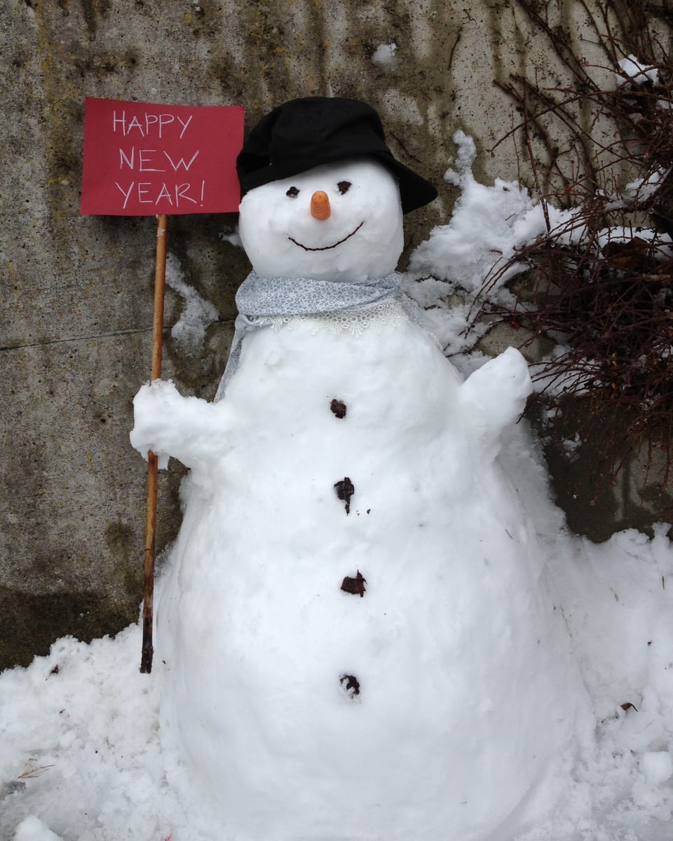 Ein Schneemann hält eine Tafel mit der Aufschrift Happy New Year.