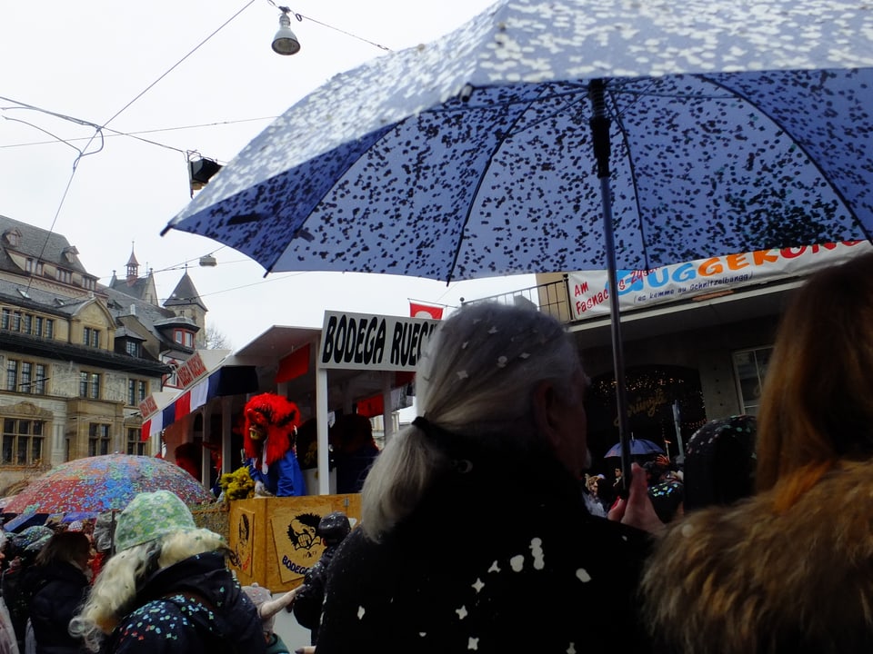 Zuschauer unter Regenschirm voller Räppli.