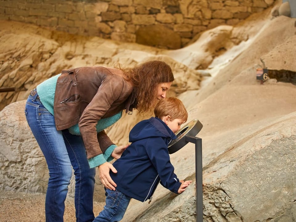 Ein Kind schaut zusammen mit seiner Mutter Versteinerungen an.