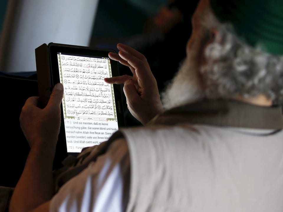 Ein Muslim liest den Koran auf einem Tablet.