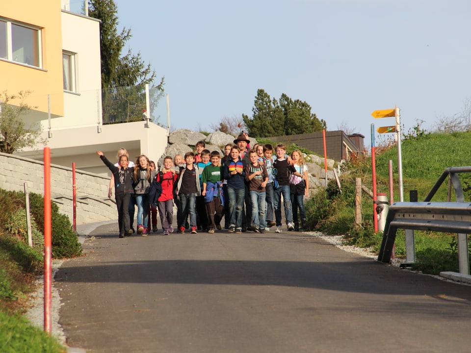 Eine Gruppe von Schülerinnen und Schülern gut gelaunt auf dem Weg Richtung Dorf.