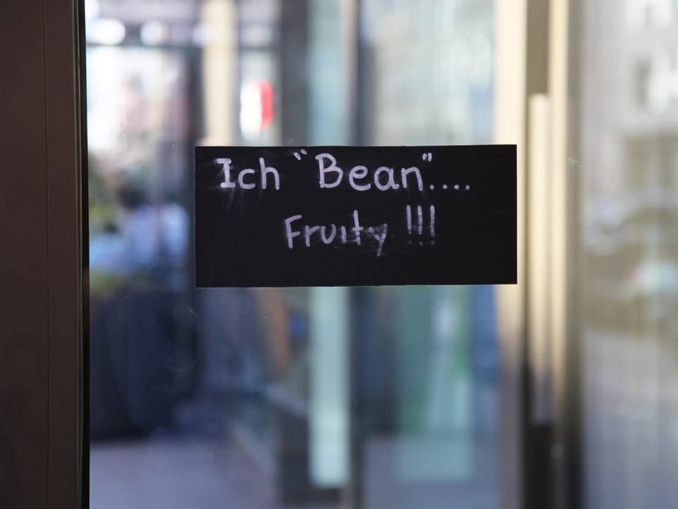 Auf einem schwarzen Schild, welches an einer Glastür angebracht ist, steht «Ich «bean» fruity»»!!!