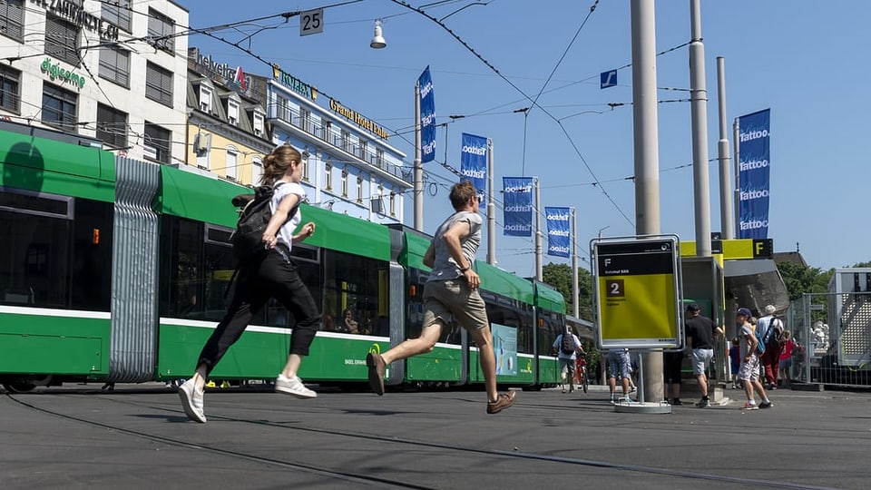 Zwei Menschen rennen neben einem Tram