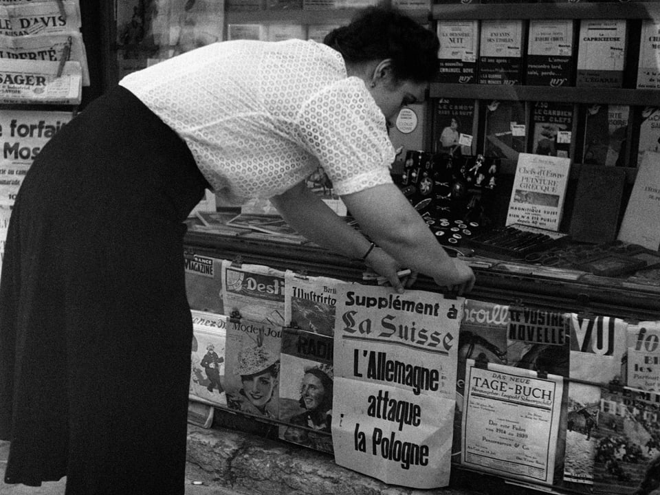 Eine Kioskfrau hängt am 2. September 1939 in Genf die Schlagzeilen aus.