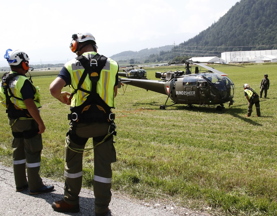 Einsatzkräfte und ein Helikopter des Bundesheeres von Österreich stehen auf einer Wiese.