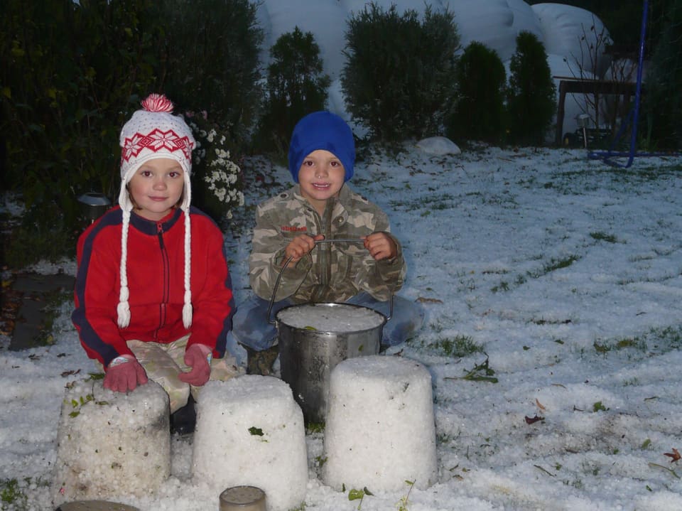 Kinder formen frisch gefallene Hagelkörner zu einem Eiskuchen. Die Aufnahme stammt von Liesberg Dorf/Baselland.