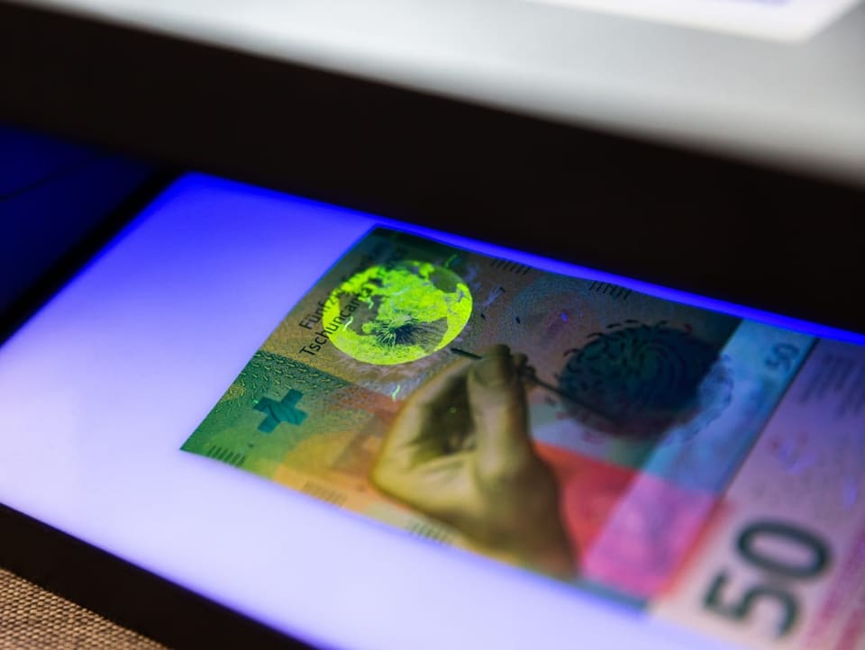 50er Note unter UV-Licht. Der Globus leuchtet hell auf.