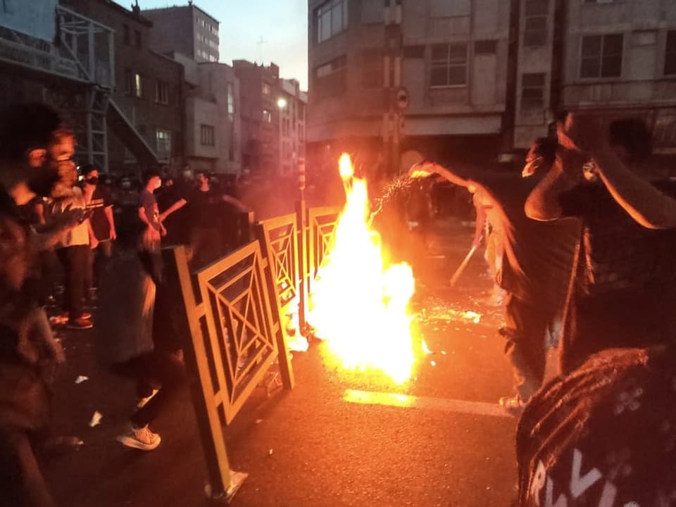 Feuer in der nächtlichen Strasse, Menschen in der Dunkelheit.