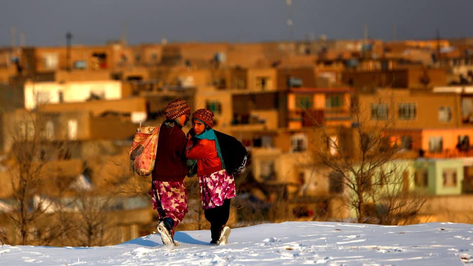 Zwei afghanische Mädchen gehen über den Schnee.
