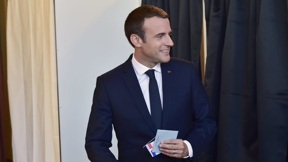 Lachender Emmanuel Macron mit Wahlcouvert.