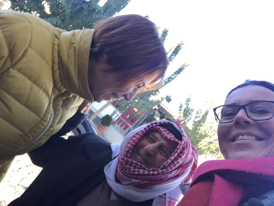 Zwei Frauen lächeln in die Kamera, hinter ihnen ein Mann mit einem Palästinenser-Tuch.