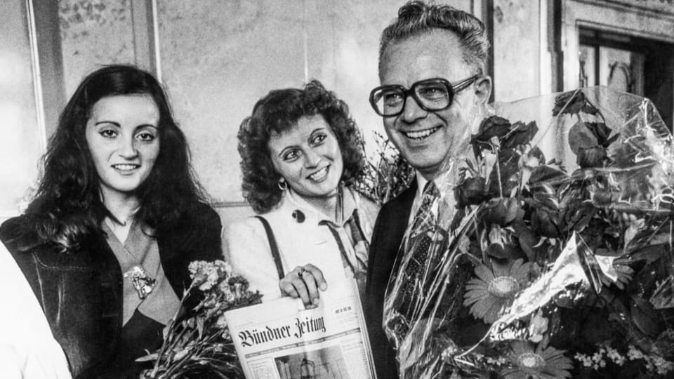 Leon Schlumpf lächelt mit seinen beiden Töchtern in die Kamera, er hält einen Blumenstrauss in der Hand.