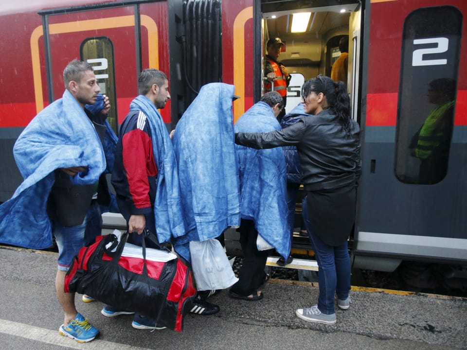 Flüchtlinge steigen in Zug ein. 