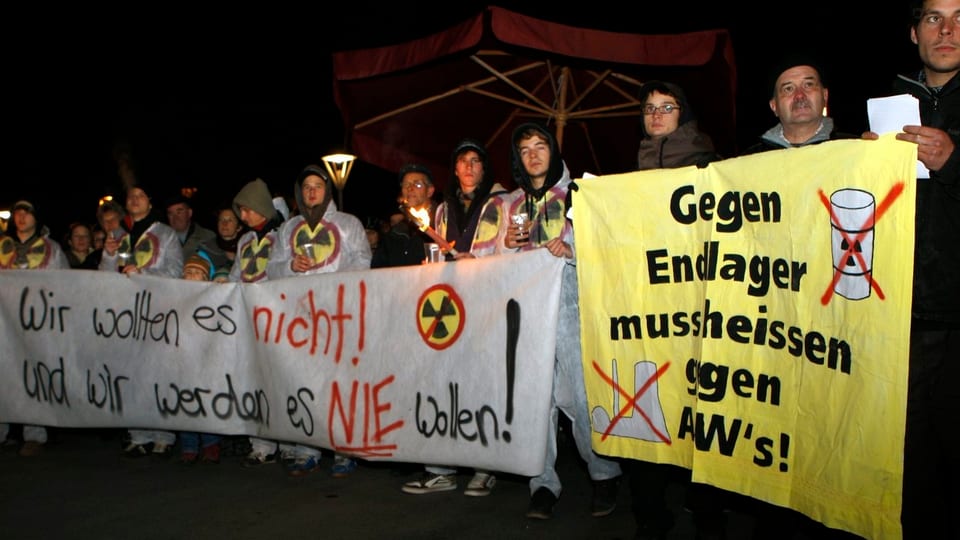 Gruppe mit Plakaten mit den Aufschriften "Wir wollen es nicht! Und wir werden es nie wollen!" sowie "Gegen Endlager muss heissen gegen AKWs"
