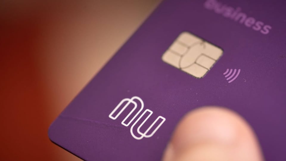 Eine lilafarbene Kreditkarte wird von jemandem in der Hand gehalten. 