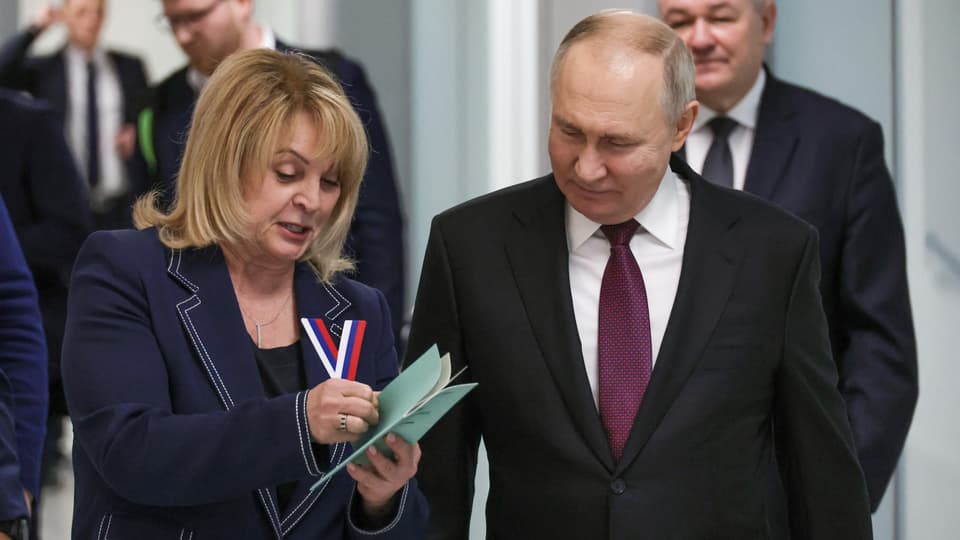 Pamfilowa und Putin gehen nebeneinander und schauen Broschüre an