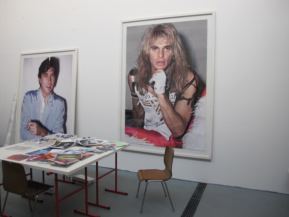 Arbeitstisch im Atelier, an der Wand gross aufgezogene Fotografien von Hannes Schmid. 