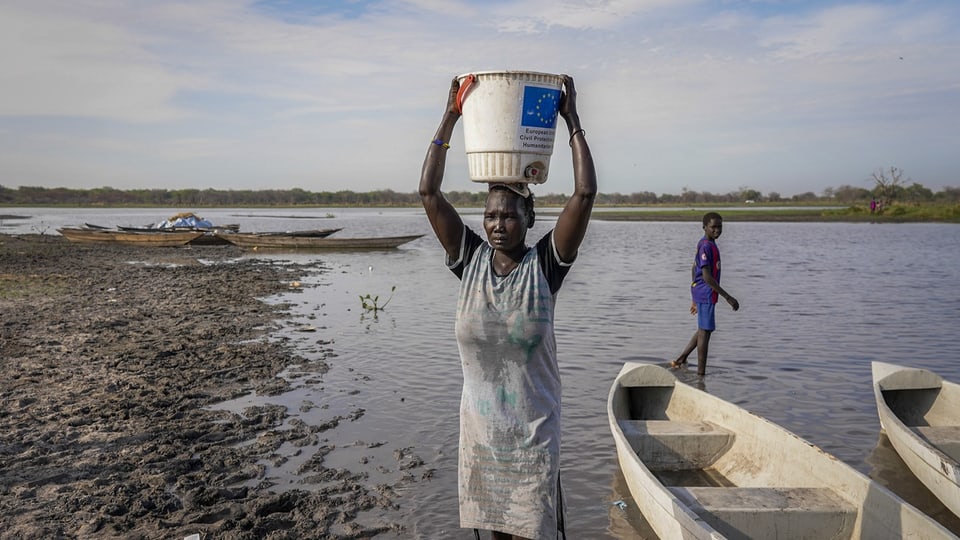 Eine Frau trägt im Südsudan Wasser aus einem Sumpf auf ihrem Kopf.