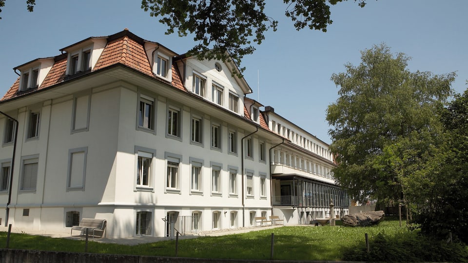 Spital Riggisberg, Altbau, besonnt, Rasen und Bäume.