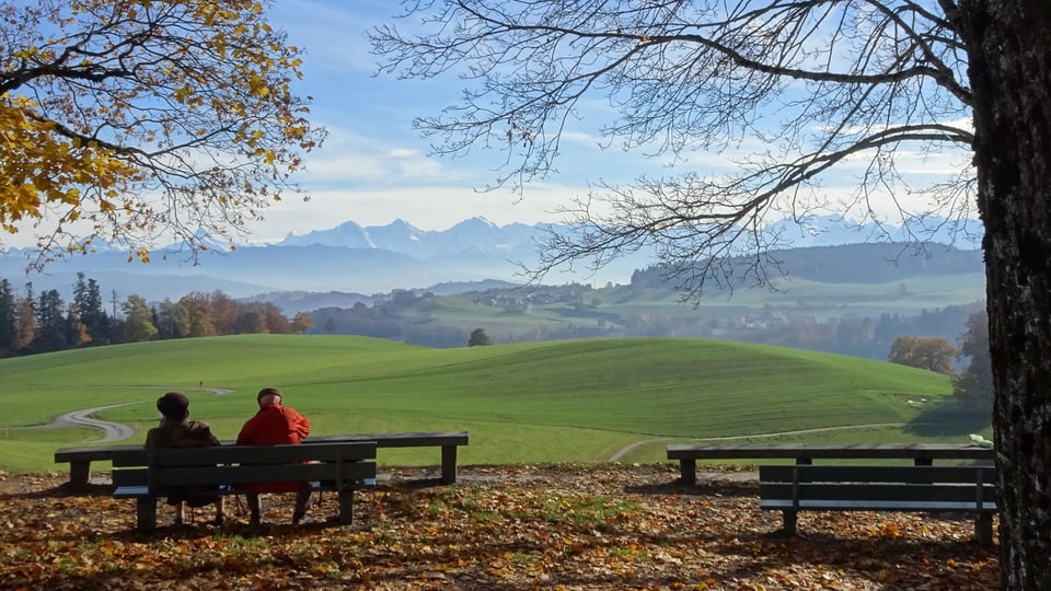 Wanderer sitzen auf einer Aussichtsbank auf dem Berner Hausberg Gurten.