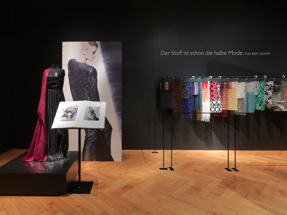 Ausstellungsraum, Foto Modell, Puppe, Stoffe und ein Zitat von Laurent: Der Stoff ist schon die halbe Mode.