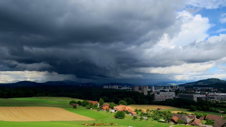 Blick von Frauenkappelen Richtung Bern. Dort ist es schwarz durch eine mächtige Gewitterwolke.