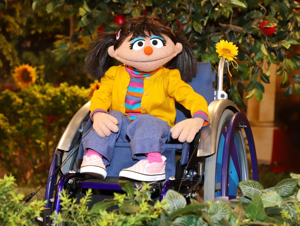 Eine Sesamstrassen-Puppe, die im Rollstuhl sitzt