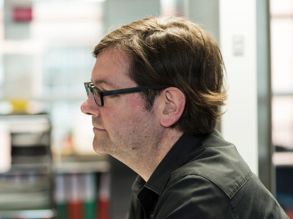 Markus Hoffmann, Produzent Echo der Zeit. Mann mit dunkler Hornbrille, schwarzem Hemnd und mittellangen Haaren von der Seite. 