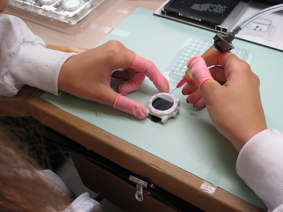 Eine Frau arbeitet mit Gummihandschuhen an einer Uhr