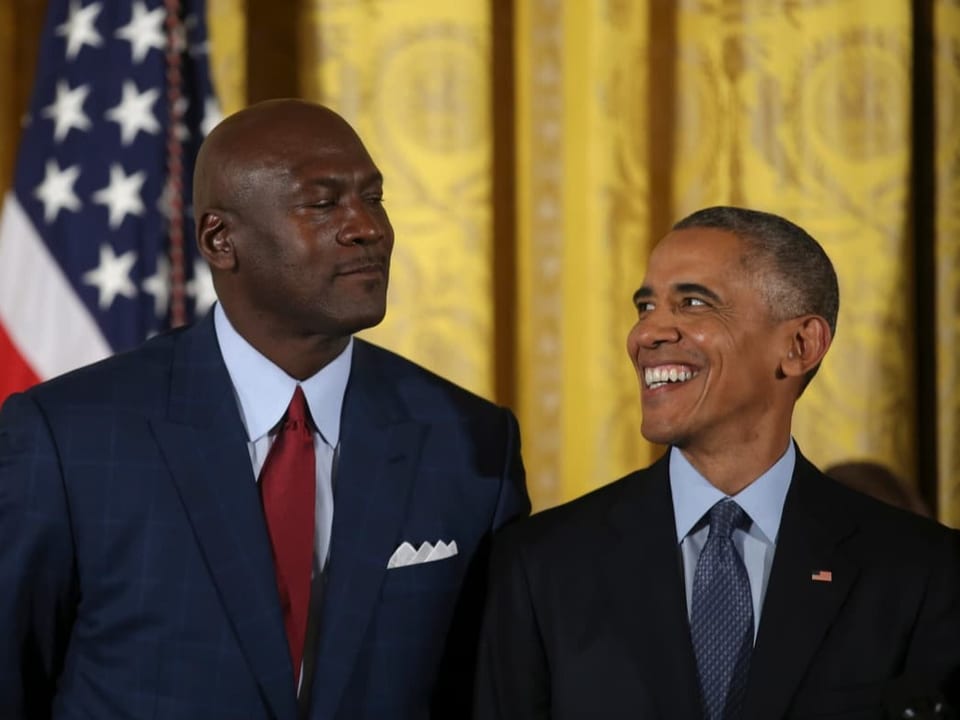 Michael Jordan steht an der Seite von Ex-US-Präsident Barack Obama vor einer US-amerikanischen Fahne.