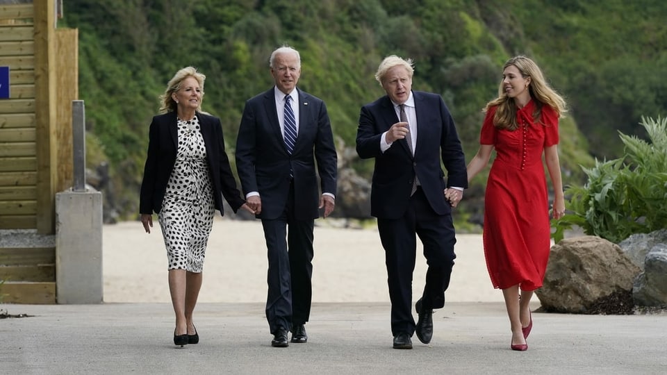 Biden und Johnson laufen zusammen mit ihren Ehefrauen in der Nähe des Meeres entlang.