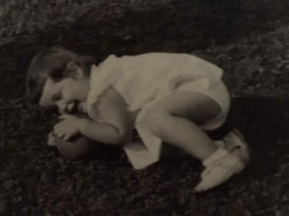 Ein Schwarz-Weiss-Foto eines Mädchens, das auf einem Rasen liegt.