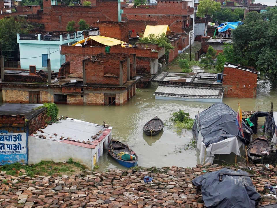 Teilweise im Wasser stehende Häuser und behelfsmässige Behausungen entlang eines Flusses