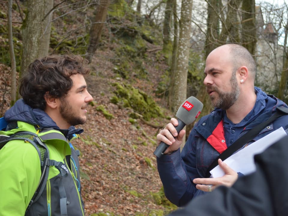 Radioreporter interviewt ein Pilgerkandidat im Wald.