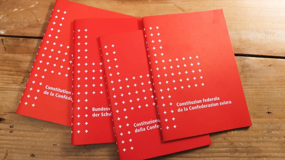 Die Schweizer Bundesverfassung liegt in den vier Landessprachen auf einer Ablage.