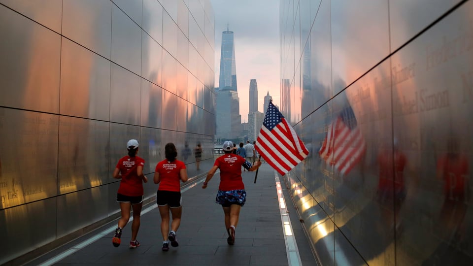 Frauen, die mit einer amerikanischen Flagge durch das Memorial von 9/11 rennen.