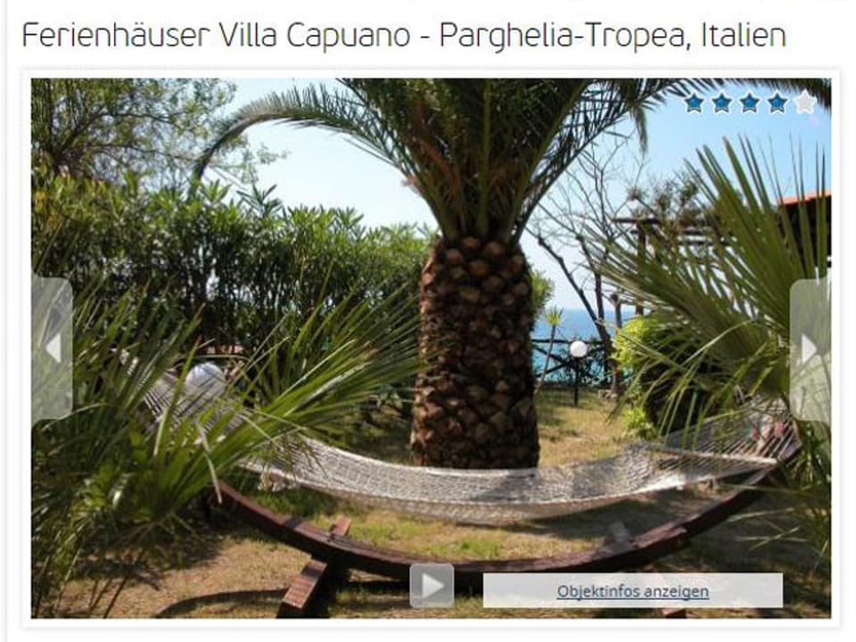 Eine schön drapierte Hängematte in einem Garten mit Palmen und Sträuchern und Aussicht aufs Meer.