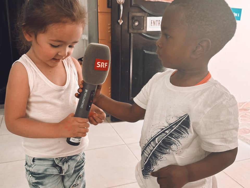 Ein Bub und ein Mädchen stehen sich gegenüber und spielen mit einem SRF-Mikrofon