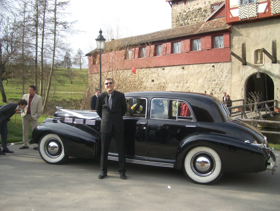 Mann posiert vor schönem Cadillac Oldtimer