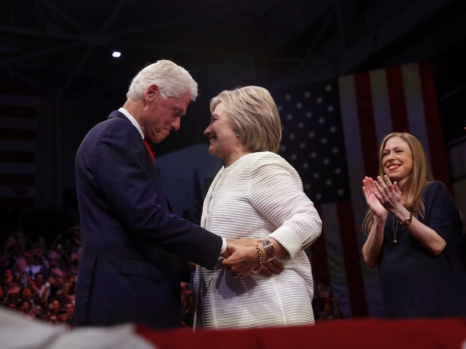 Hillary Clinton und Bill umarmen sich. Dahinter klatscht Tochter Chelsea Beifall.