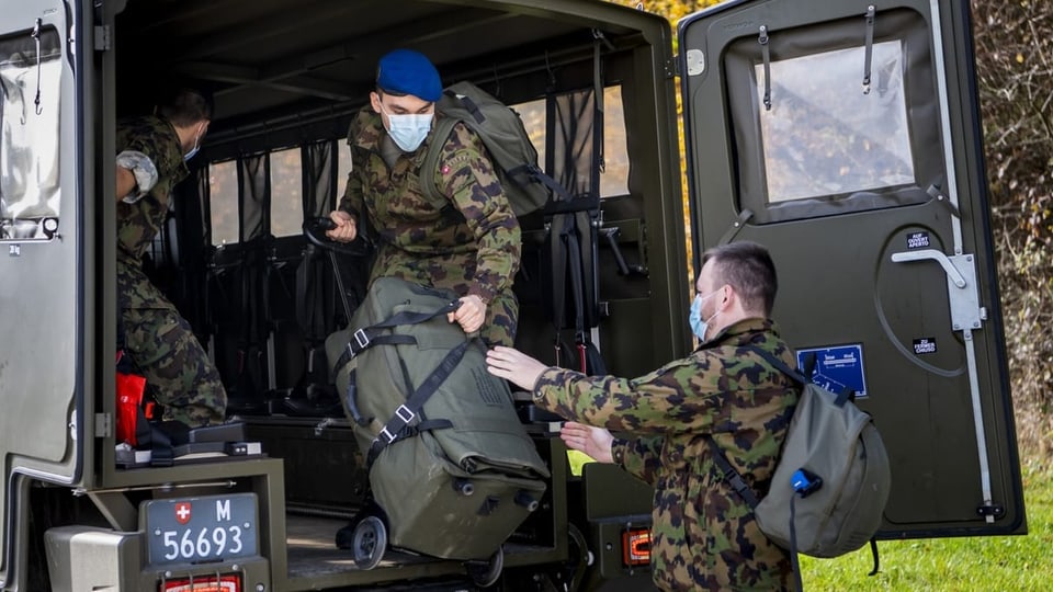 Militärangehörige packen Gepäck in ein Militärfahrzeug.