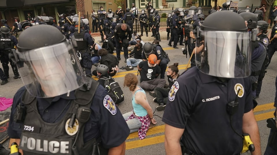 Demonstranten mit gefesselten Händen sitzen am Boden