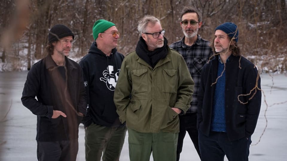 Fünf Männer mittleren Alters stehen im verschneiten Park